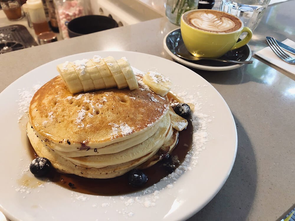 Pancakes in Bakers & Roasters with banana on top and cappuccino with art